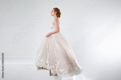 Portrait of a beautiful girl in a wedding dress. Concept of bride going towards future happiness  white background