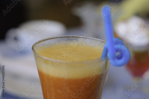 Glass with carrot smoothie and blue straw
