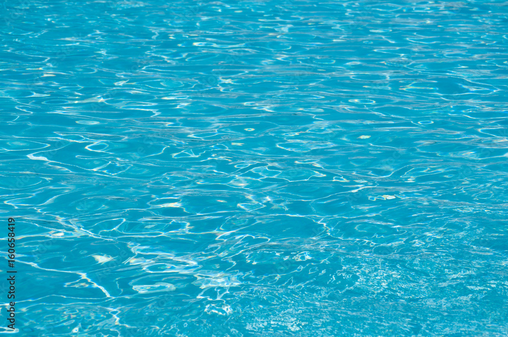 Blue ripple water surface with sun reflection in the swimming pool