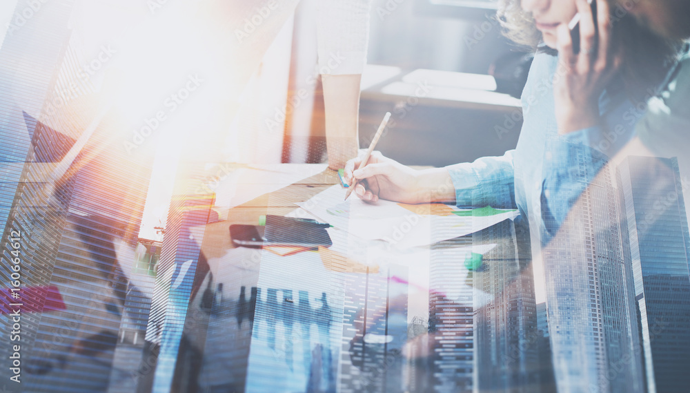 Fototapeta premium Business people working process concept.Young coworkers working together in modern office.Woman using mobile phone.Double exposure,skyscraper building blurred background.Horizontal.