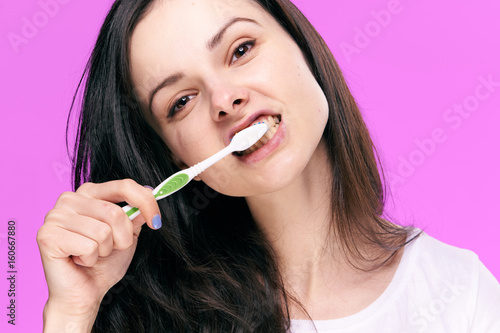 Oral care, a woman brushes teeth on a pink background