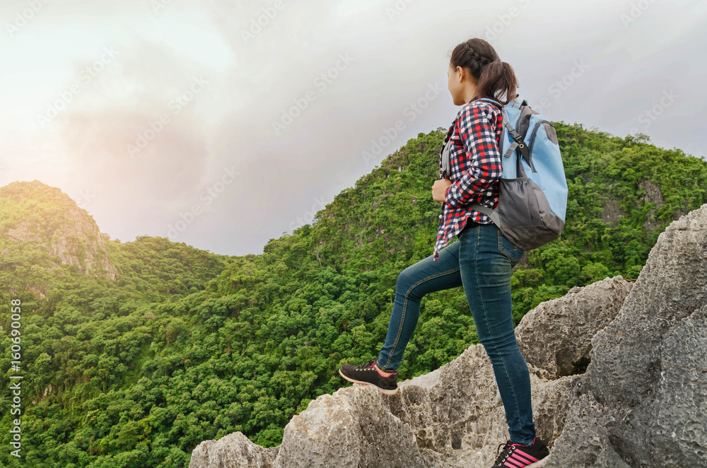 Fototapeta premium Happy beautiful woman traveler with backpack standing on top of a mountain and enjoying sunset view of thailand
