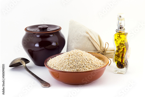 The composition of the Barley groats in a clay pial next to a clay pot and a copper spoon, photo