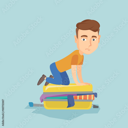 Young man trying to close suitcase.