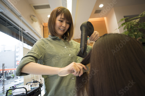 Hairdresser is styling female hair