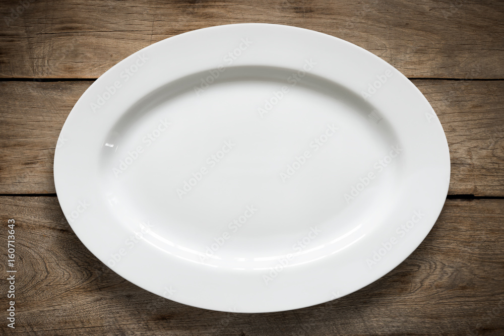 Top view of empty white food plate on a wood background. Top view of empty white food plate on a wood background.