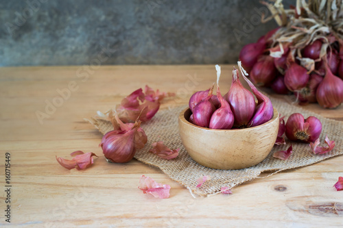 the shallots in bowl on old wooden table with old wallpaper background