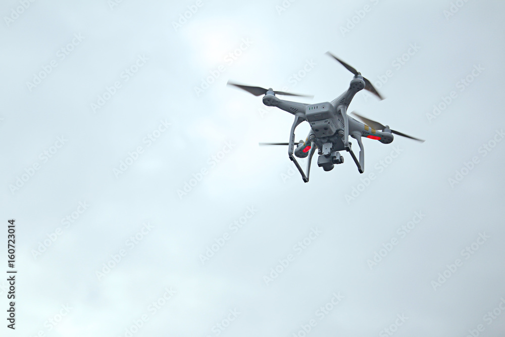 White drone with digital camera flying on sky background. White drone with digital camera flying on sky background.