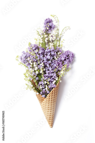 Waffle cone with lily of the valley and lilac flowers photo