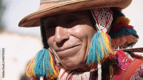 Native quechua man using a colorful hancrafted chullo and a highlander hat smiling and singing. Slow motion photo