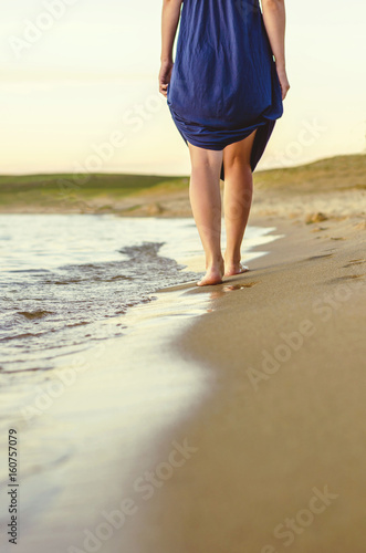 Girl walking on sand beach leaving footprints in the sand at sunset © Maksim