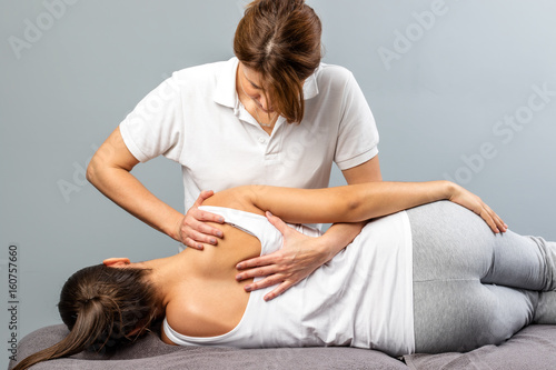 Billede på lærred Female therapist manipulating shoulder blade on young female patient