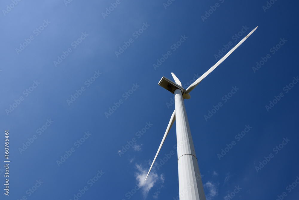 White wind turbine generating electricity on blue sky White wind turbine generating electricity on blue sky