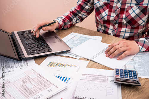 man filling tax form with business report, chart, laptop