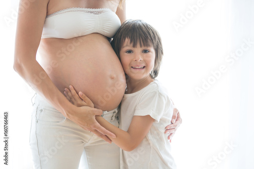 Portrait of beautiful pregnant woman and her cute child, isolated image