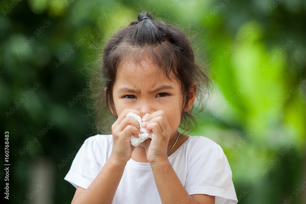 Sick little asian girl wiping or cleaning nose with tissue on her hand Sick little asian girl wiping or cleaning nose with tissue on her hand