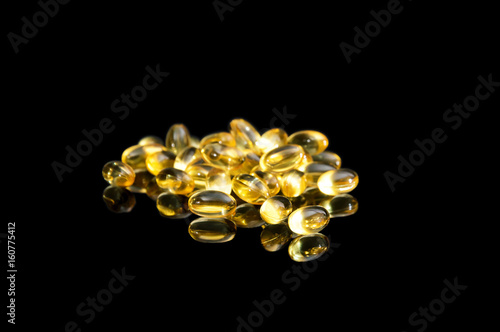 Yellow pills on the black reflective background.