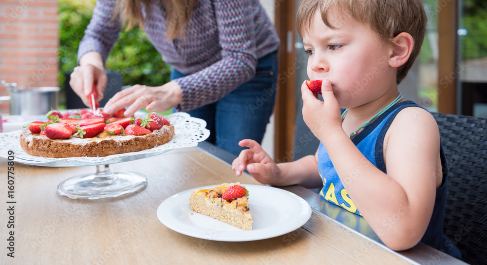 Kid eating a strawberry pie on a outdoor table Kid eating a strawberry pie on a outdoor table