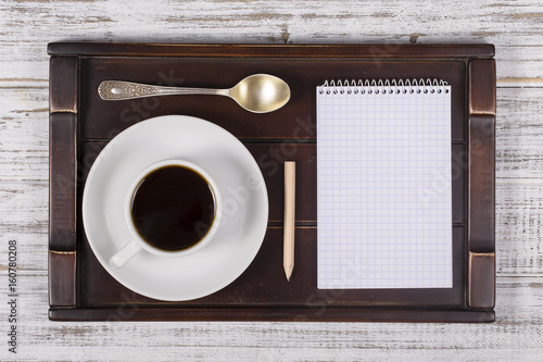Coffee cup with note book on a tray on white wooden table. Lifestyle concept. Close up, top view