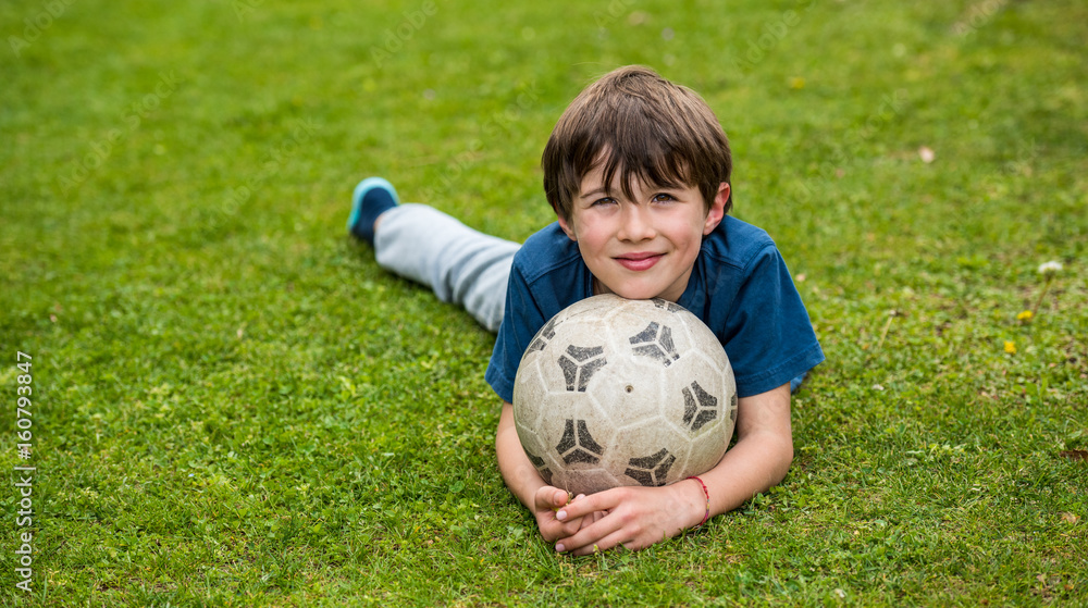Young boy laying on the grass holding a soccer ball Young boy laying on the grass holding a soccer ball