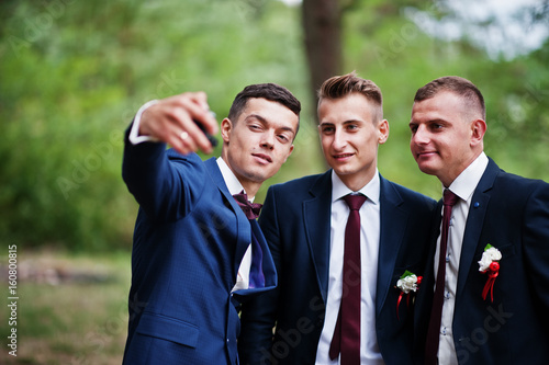 Handsome groom with cool groomsmen walking in the forest and having fun on a wedding day.