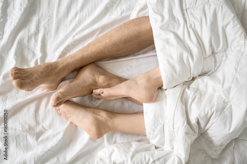 Legs of lovers under blanket