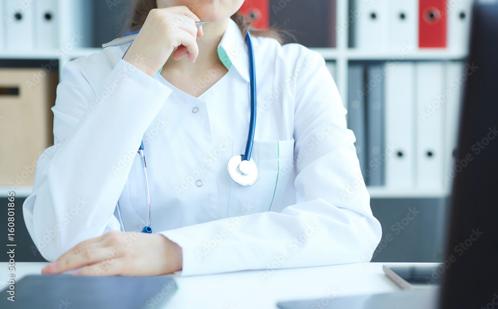 Middle section of female medicine doctor sitting at the table and working at the laptop. Middle section of female medicine doctor sitting at the table and working at the laptop.