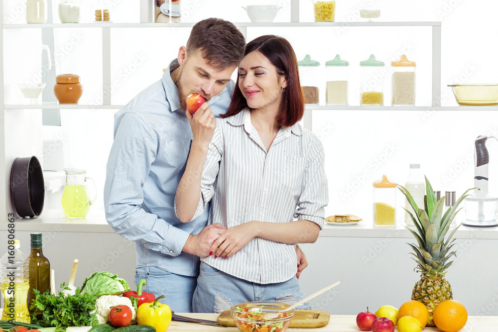 Loving happy couple eating apple in kitchen Loving happy couple eating apple in kitchen