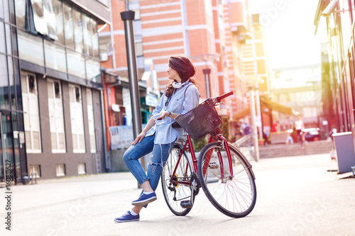 Beautiful young woman with bicycle in urban environment.