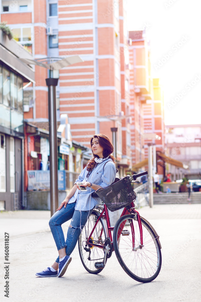 Fototapeta premium Beautiful young woman with bicycle in urban environment.