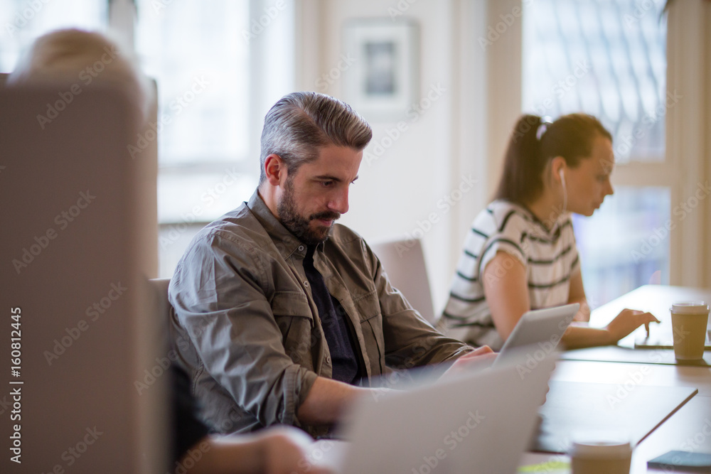 Freelancers working in a shared office deskspace Freelancers working in a shared office deskspace