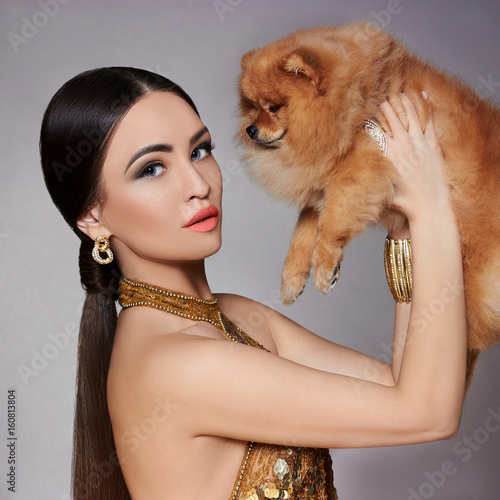 Portrait of a fashion model with a small dog in his hands
