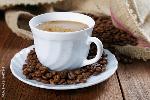 Cup with coffee on the table next to coffee beans