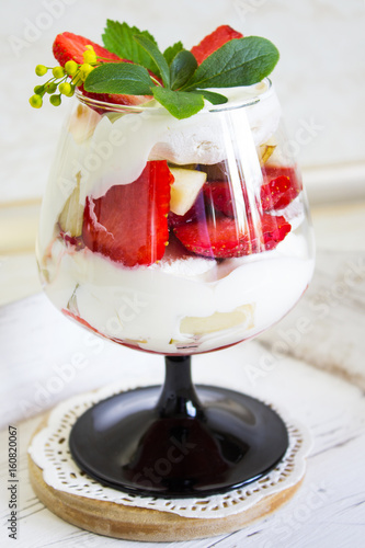 Summer strawberry dessert in a glass cup. Dessert with strawberries and sour cream. Selective focus. Vertical. photo