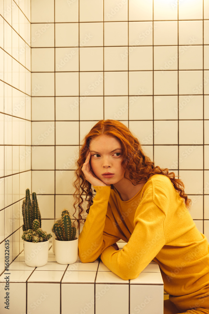 Concentrated young redhead curly lady sitting in cafe Concentrated young redhead curly lady sitting in cafe