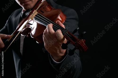 Violin player hands. Musician, virtuoso, violinist playing violin against the background of musical notes. Close up of musical instruments, fiddle with fiddlestick
