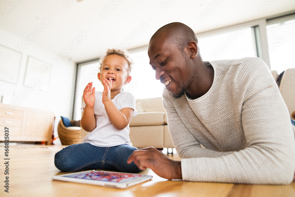 Afro-american father with little daughter with tablet at home. Afro-american father with little daughter with tablet at home.