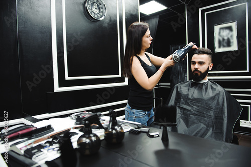 Master cuts hair and beard of men in the barbershop  hairdresser makes hairstyle for a young man