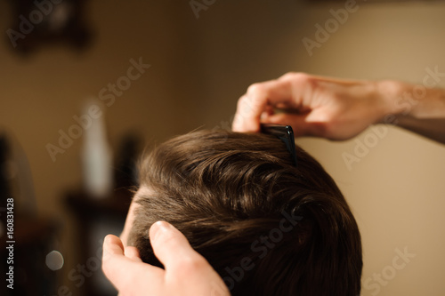 Master cuts hair and beard of men in the barbershop