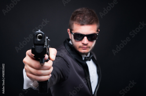 Handsome murderer aiming gun to an invisible target