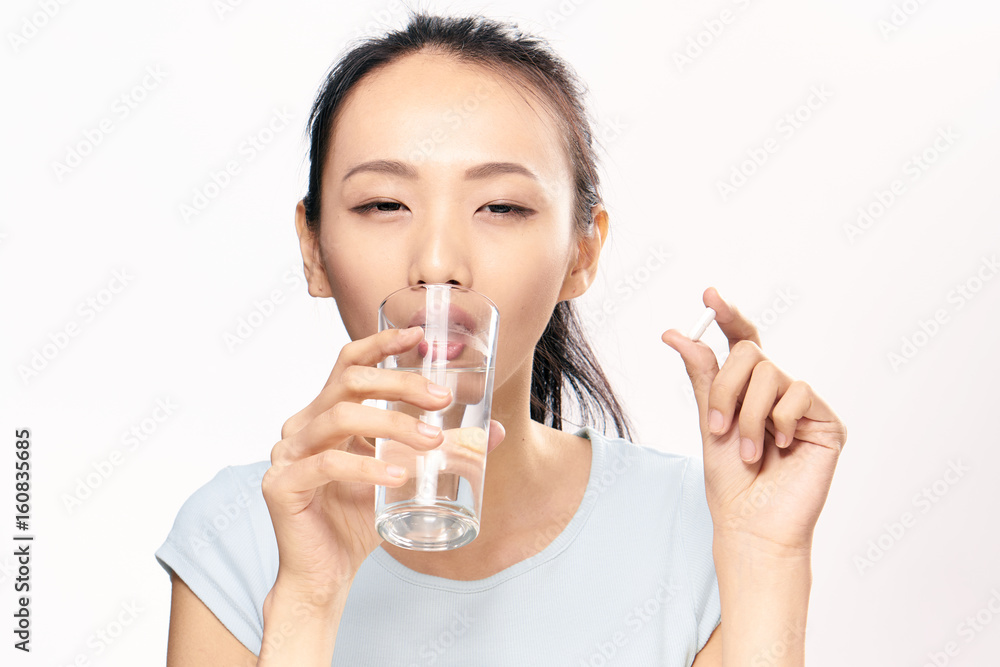 Woman is sick, woman is drinking a pill with water, woman with pill and glass of water background Woman is sick, woman is drinking a pill with water, woman with pill and glass of water background