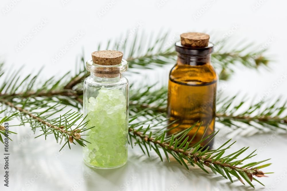 Bottles of essential oil and fir branches for aromatherapy and spa on white table background Bottles of essential oil and fir branches for aromatherapy and spa on white table background