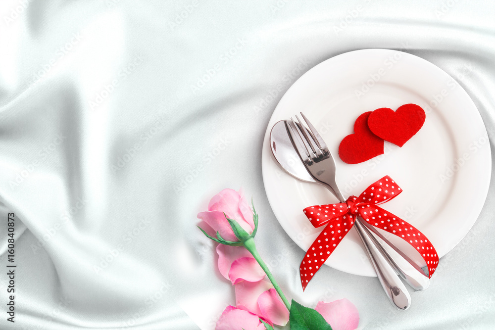 red heart shape with White empty plate with fork and spoon on white silk fabric for love dinner concept red heart shape with White empty plate with fork and spoon on white silk fabric for love dinner concept