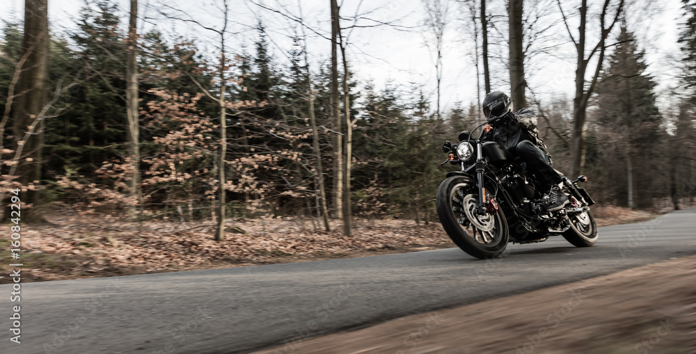 Obraz premium Man riding sportster motorcycle during sunset.