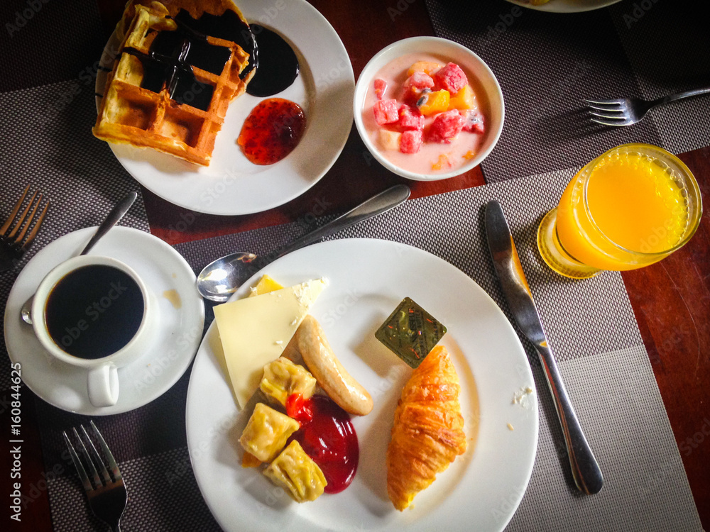Tasty hearty breakfast served with coffee, orange juice, cheese, fruit yogurt and waffles