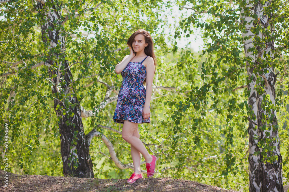 Beautiful girl in a multi-colored dress with long hair in the forest in summer