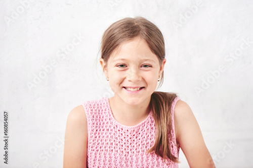 Portrait of a little girl on the white background of the wall