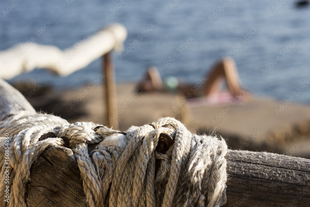 Fototapeta premium Kamienista plaża w Chorwacji z perspektywy drewnianej poręczy / Kobieta w tle