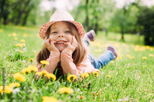 Cute little girl with hat lying on the grass