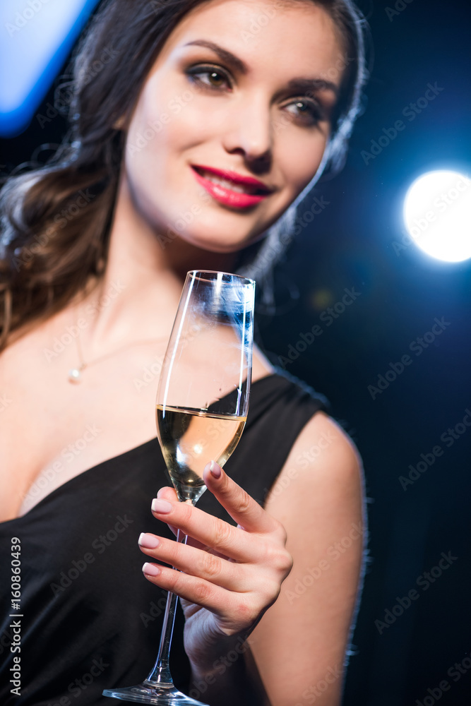 Close-up view of smiling brunette woman holding wine glass looking away Close-up view of smiling brunette woman holding wine glass looking away